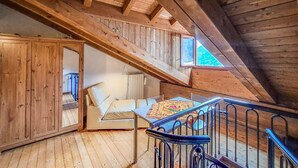 Dormitorio estilo loft con cama de madera, sofá, mesa y ventana.
