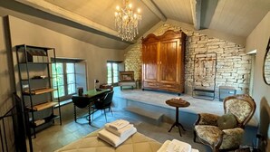 A room with a stone fireplace, a chandelier, a bed with a quilted cover, a desk with a chair, and a bookshelf. - Panoramic house, swimming pool, between langhe and monferrato (Castelletto d'Erro)