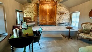 A room with a stone wall, a wooden cabinet, a dining table with chairs, a small round table, and a sofa. - Panoramic house, swimming pool, between langhe and monferrato (Castelletto d'Erro)