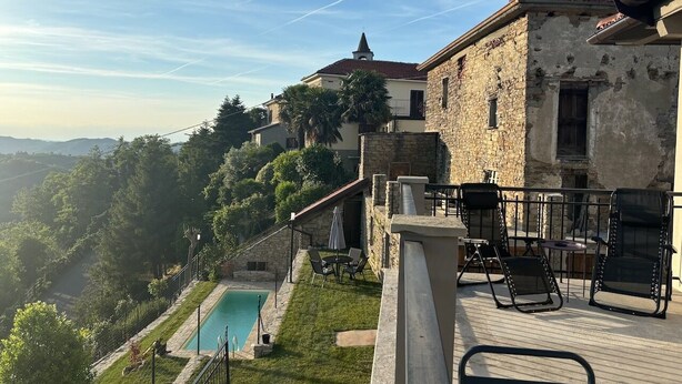 A stone building with a pool, outdoor seating, and a view of a forested area. - Panoramic house, swimming pool, between langhe and monferrato (Castelletto d'Erro)