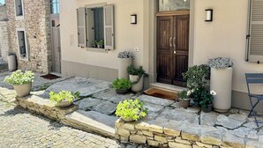 A modern building with a stone facade, a wooden door, and several potted plants. - Panoramic house, swimming pool, between langhe and monferrato (Castelletto d'Erro)
