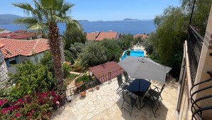 A patio with outdoor furniture, a swimming pool, and a view of the sea.