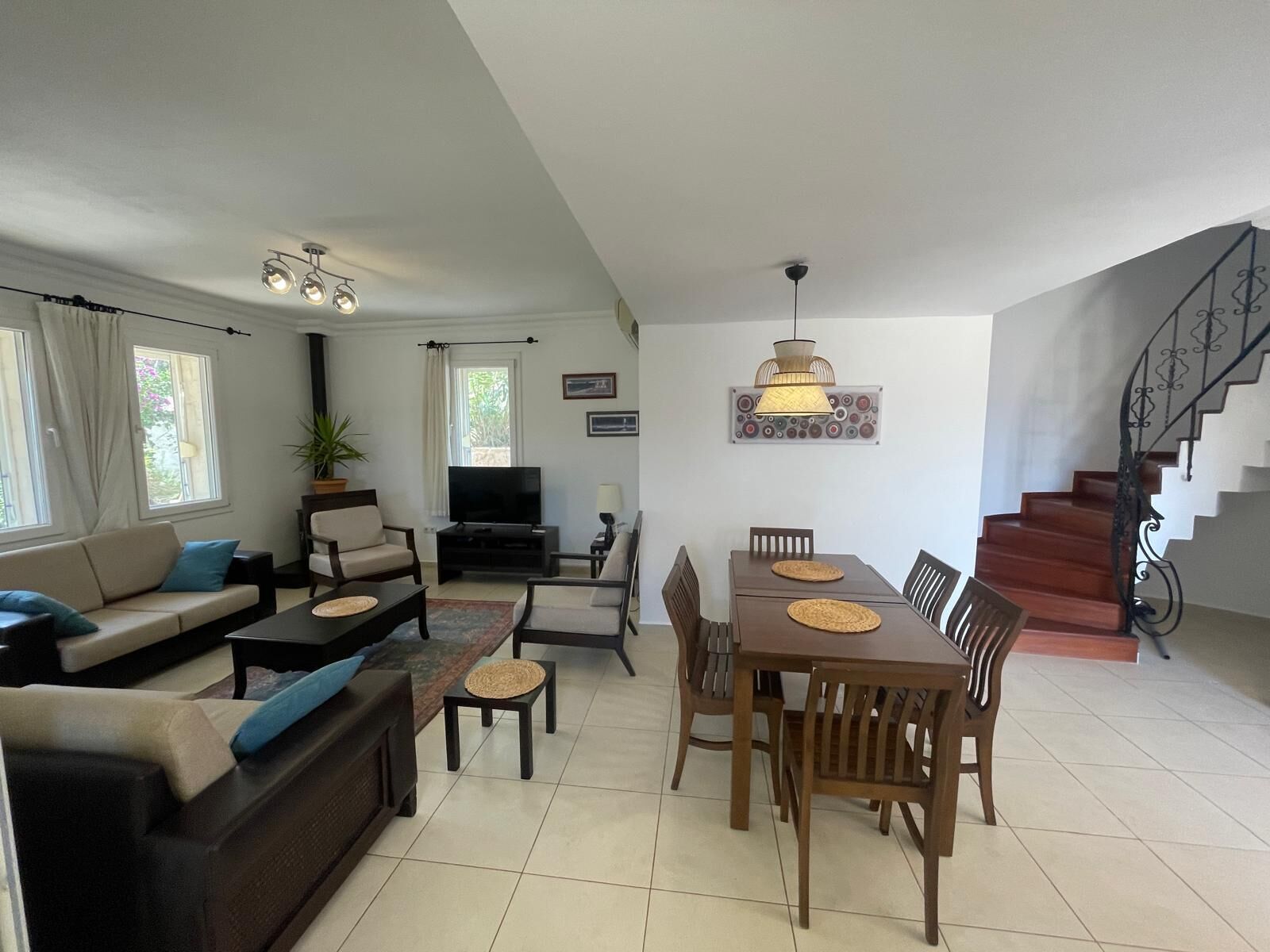 Un salon comprenant un canapé, un téléviseur, une table à manger, des chaises et un escalier.