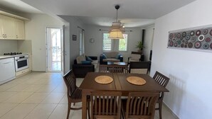 A modern kitchen with a dining area, a sofa set, and a decorative wall piece.