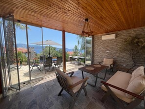 Eine moderne Terrassenanlage im Freien mit Blick aufs Meer, einer Steinsäule und einer Holzbeschichtung.