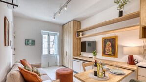 Una sala moderna con sofá, reposapiés, mesa de comedor y zona de cocina.