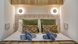Una cama con dos almohadas, un cabecero con luces circulares y un panel de madera en la parte superior.