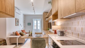 Una cocina moderna con armarios de madera, un comedor con mesa y sillas, y vistas al exterior por una puerta.