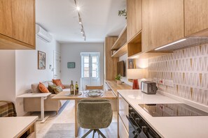 Eine moderne Küche mit Holzausstattung, ein Essbereich mit Tisch und Stühlen sowie ein Blick ins Freie durch eine Tür.