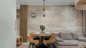Ein stilvoller Essbereich mit einem runden Tisch, vier Stühlen, einer Vase mit Blumen, einer Uhr und einer strukturierten Wand.