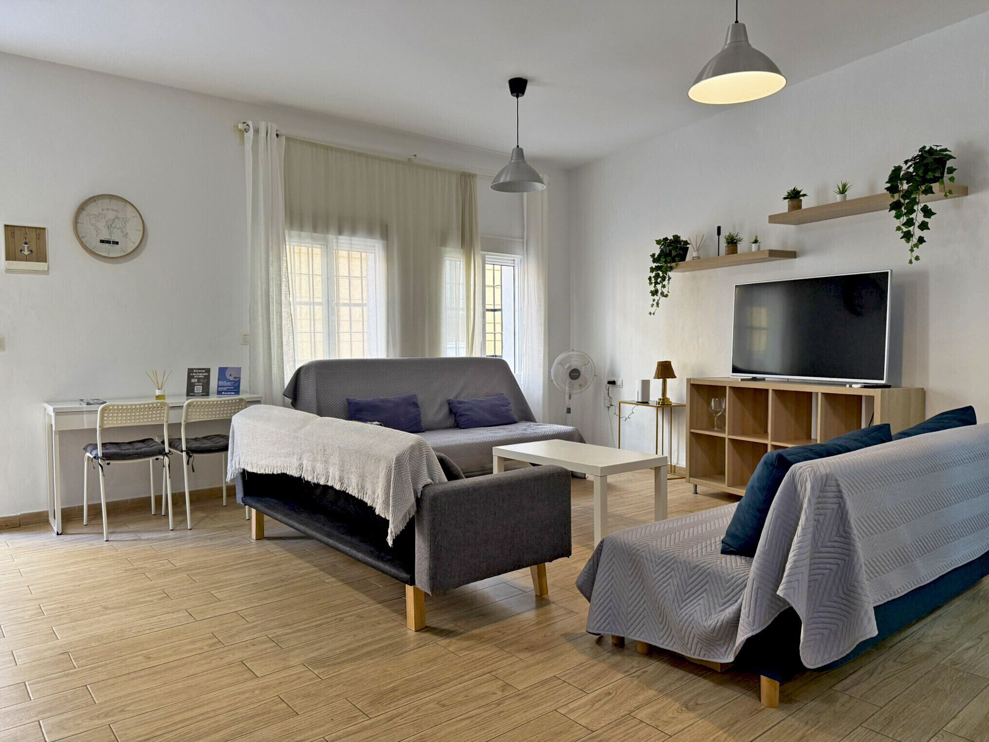 Un salon moderne comprenant un canapé, une table basse, un téléviseur et un bureau.