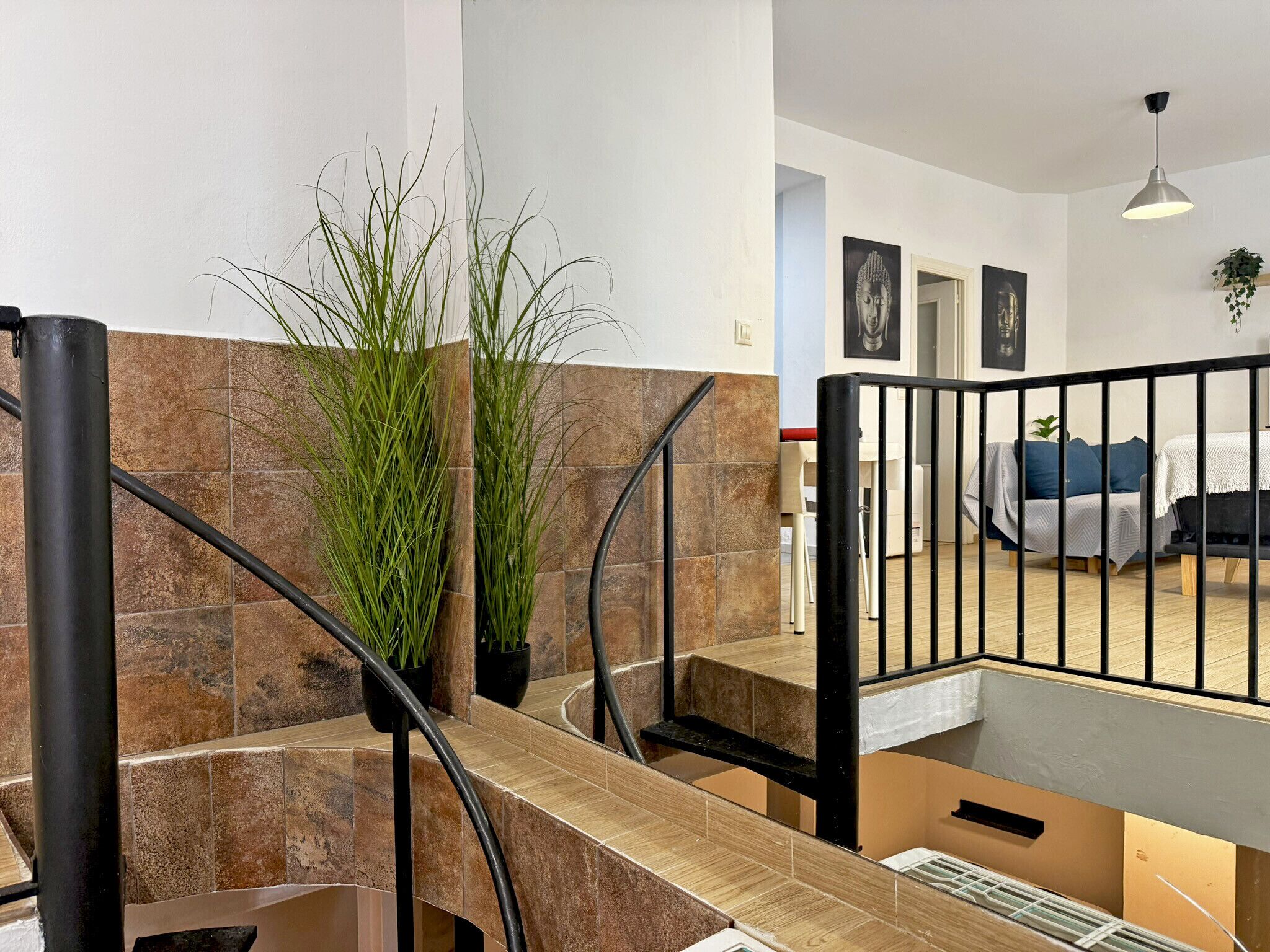 A modern interior with a staircase, potted plants, and a dining area.