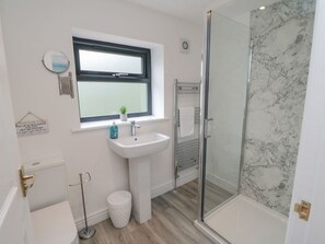 A modern bathroom with a glass shower enclosure, a sink with a mirror, and a toilet. - Riverside House (Scarborough)