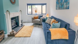 A living room with a fireplace, a sofa, a rug, and a large window. - Riverside House (Scarborough)