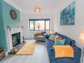 A living room with a fireplace, a sofa, a rug, and a large window. - Riverside House (Scarborough)