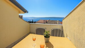 A balcony with a table, two chairs, a potted plant, and two glasses of wine. - Well-kept vacation accommodation with private balcony and sea view (Dramalj)