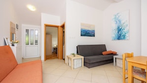 A living room with a sofa, a dining table, and a small side table. - Well-kept vacation accommodation with private balcony and sea view (Dramalj)