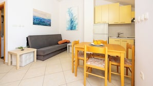 A compact living space with a sofa, a dining table with chairs, a small side table, and a kitchen area with cabinets and a sink. - Well-kept vacation accommodation with private balcony and sea view (Dramalj)