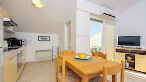 A compact kitchen with a dining table, chairs, a microwave, and a TV. - Well-kept vacation accommodation with private balcony and sea view (Dramalj)