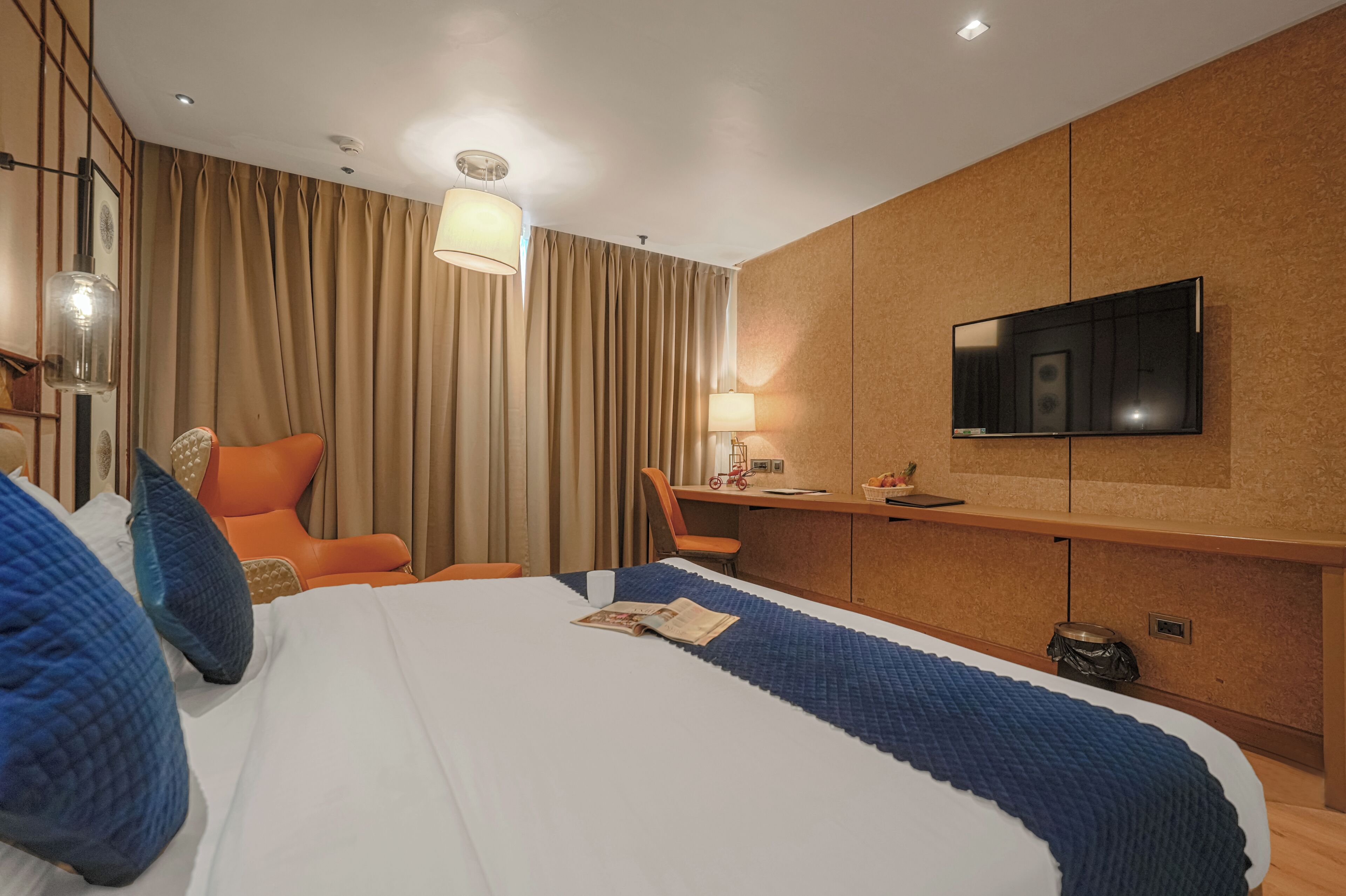 A hotel room with a bed, a desk, a chair, a television, and a window with curtains.