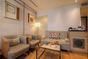 A modern living room with two sofas, a coffee table with fruit, a lamp, and a small side table with a bottle. - Ramee Collection Airport Road Mohali (Mohali)