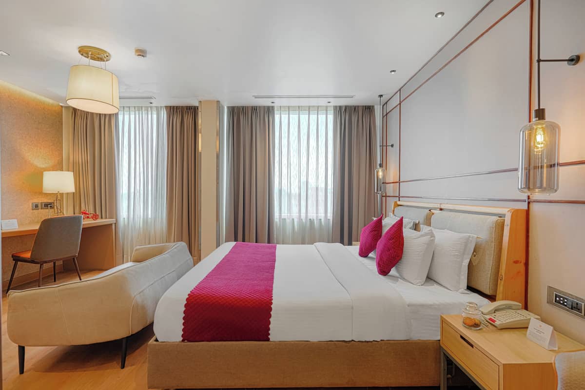Una habitación de hotel con cama, escritorio, silla, lámpara y teléfono.