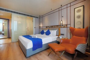 A modern hotel room with a bed, a chair, a nightstand, and a wall with artwork. - Ramee Collection Airport Road Mohali (Mohali)