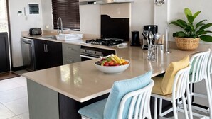 Une cuisine moderne dotée d’un îlot central, de tabourets de bar, d’une cuisinière et d’un évier.