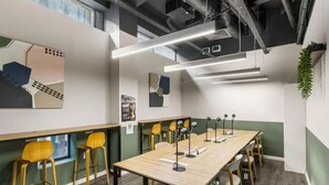 A conference room with a long table, multiple chairs, and a green accent wall. - Student Only Bronze Ensuite at Highbury  (London)