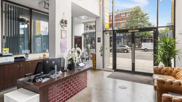 A reception area with a desk, computer, and a plant. - Student Only Bronze Ensuite at Highbury  (London)