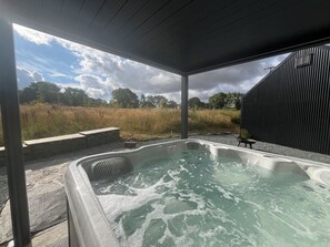 Ein Whirlpool mit Blick auf ein Feld und ein Gebäude im Hintergrund.