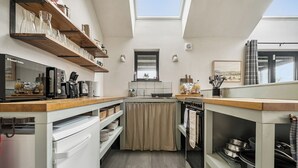 A compact kitchen with a wooden countertop, a built-in oven, and a window above the sink. - Grove Cottage (Kington)