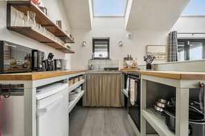 A compact kitchen with a wooden countertop, a built-in oven, and a window above the sink. - Grove Cottage (Kington)