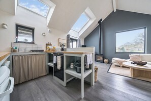 A modern kitchen with skylights, a dining area with a sofa, and a large window with a view. - Grove Cottage (Kington)