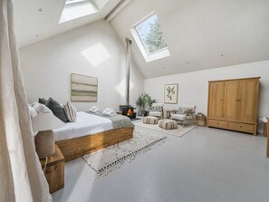 Ein Schlafzimmer mit Dachfenster, Bett, Kleiderschrank, Kamin und Fenster.