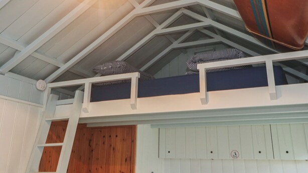 A loft-style bedroom with a sloped ceiling, wooden beams, and a bunk bed. - Pleasans (Hayle)