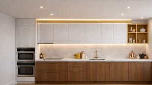A modern kitchen with built-in appliances, wooden cabinets, and a marble countertop. - Cozy 2-Bed in Central London (London)