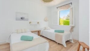 Una habitación con dos camas, una ventana con vistas y una mesita.