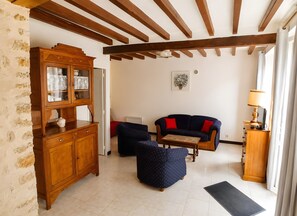 Una sala de estar con un aparador de madera, un sofá azul con cojines rojos, una mesita y una lámpara.