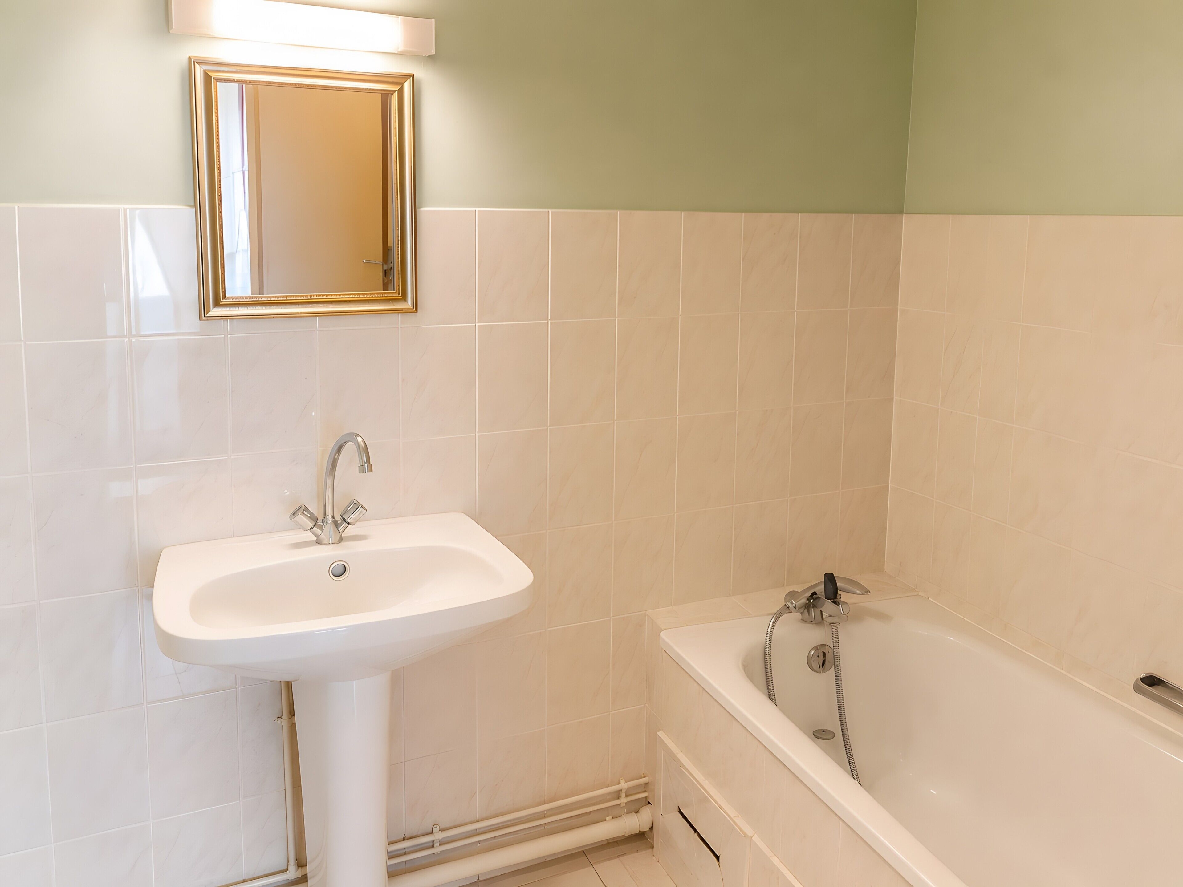 A bathroom with a sink, mirror, and bathtub.