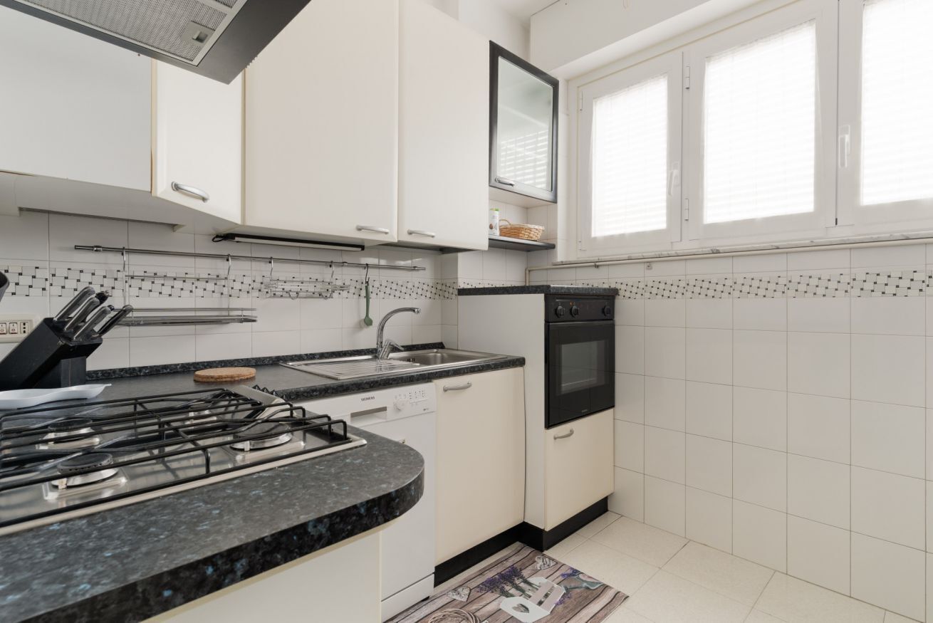 Een moderne keuken met witte kasten, een gasfornuis, een spoelbak en een zwarte oven.