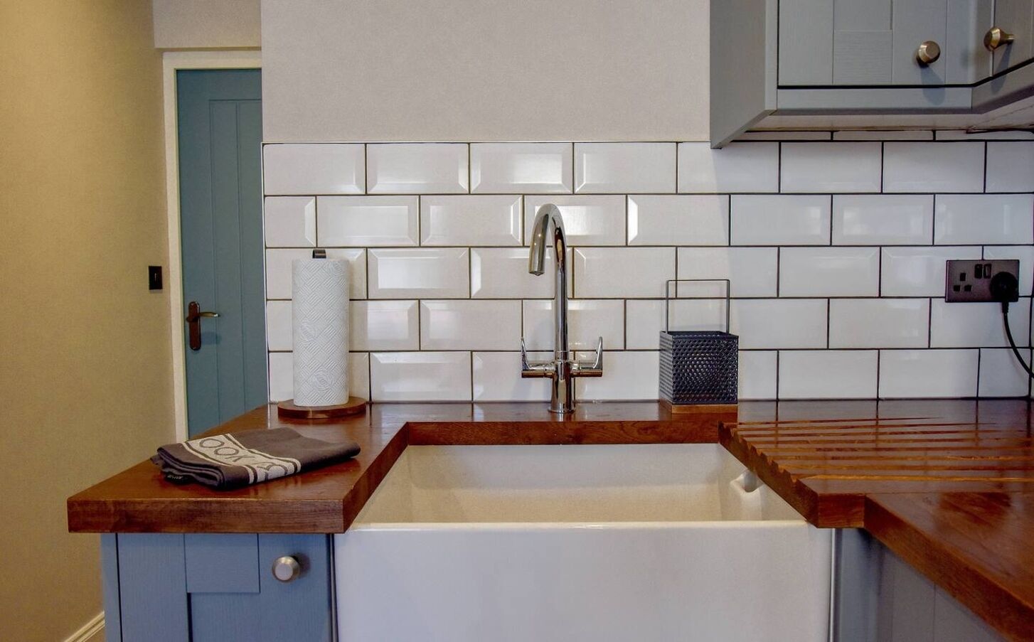 A kitchen with a sink, a towel, a paper towel holder, and a power outlet.