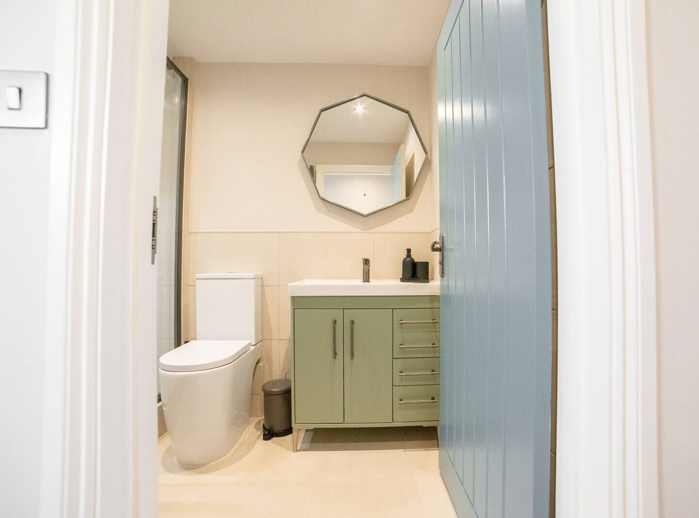 A bathroom with a toilet, a sink, a mirror, and a cabinet.