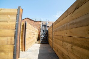 Un estrecho pasillo de madera con una escalera de metal que conduce a un edificio de ladrillo.