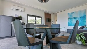 A modern kitchen with a built-in oven, a dining area with a glass table and chairs, and a large abstract painting on the wall. - Aria Art Suite   Lake View Terrace and Private Hot Tub (BARDOLINO)