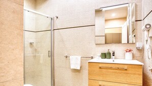 Een moderne badkamer met een douchecabine van glas, een houten wastafelmeubel met spiegel en een handdoekrek.