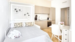 Een moderne hotelkamer met een bed, een bureau, een kitchenette en een badkamer.