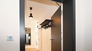 Un couloir doté d’un plancher en bois, d’une porte à cadre noir, d’un luminaire suspendu et d’un porte-manteau.