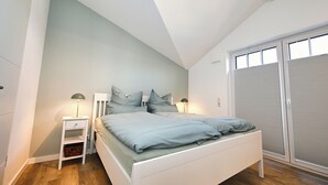 Une chambre à coucher avec un lit, des tables de chevet, une lampe, une fenêtre et une porte coulissante.