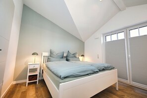 Une chambre à coucher avec un lit, des tables de chevet, une lampe, une fenêtre et une porte coulissante.